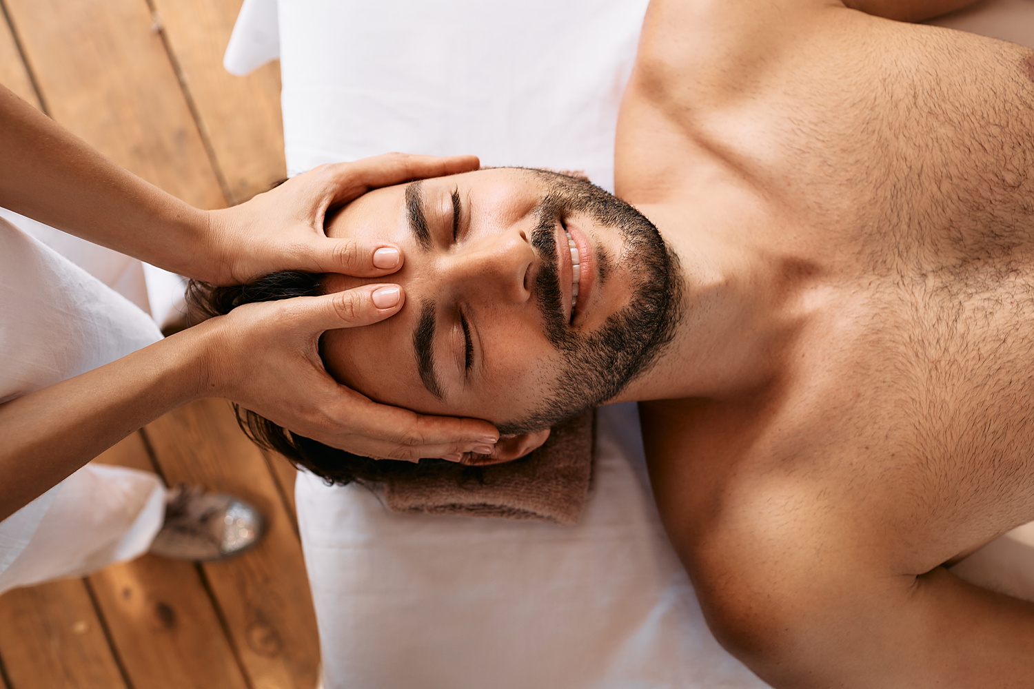 Relaxing anti-stress head massage. Handsome man relaxes in a massage parlor during head massage, top view